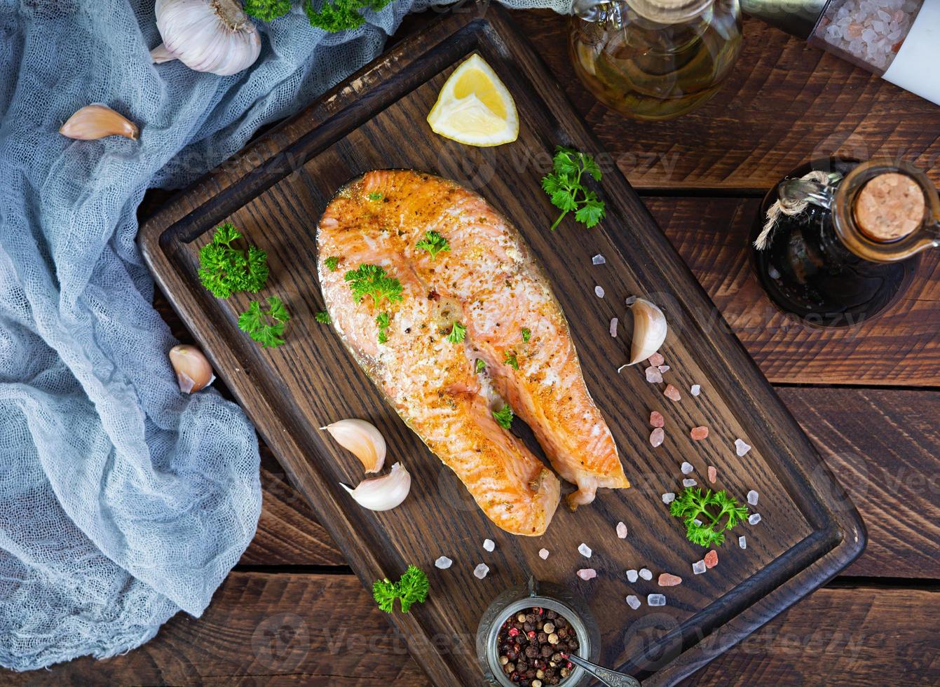 filete de salmón al horno con hierbas en tabla de cortar de madera. salmón a la plancha con sal y pimienta foto