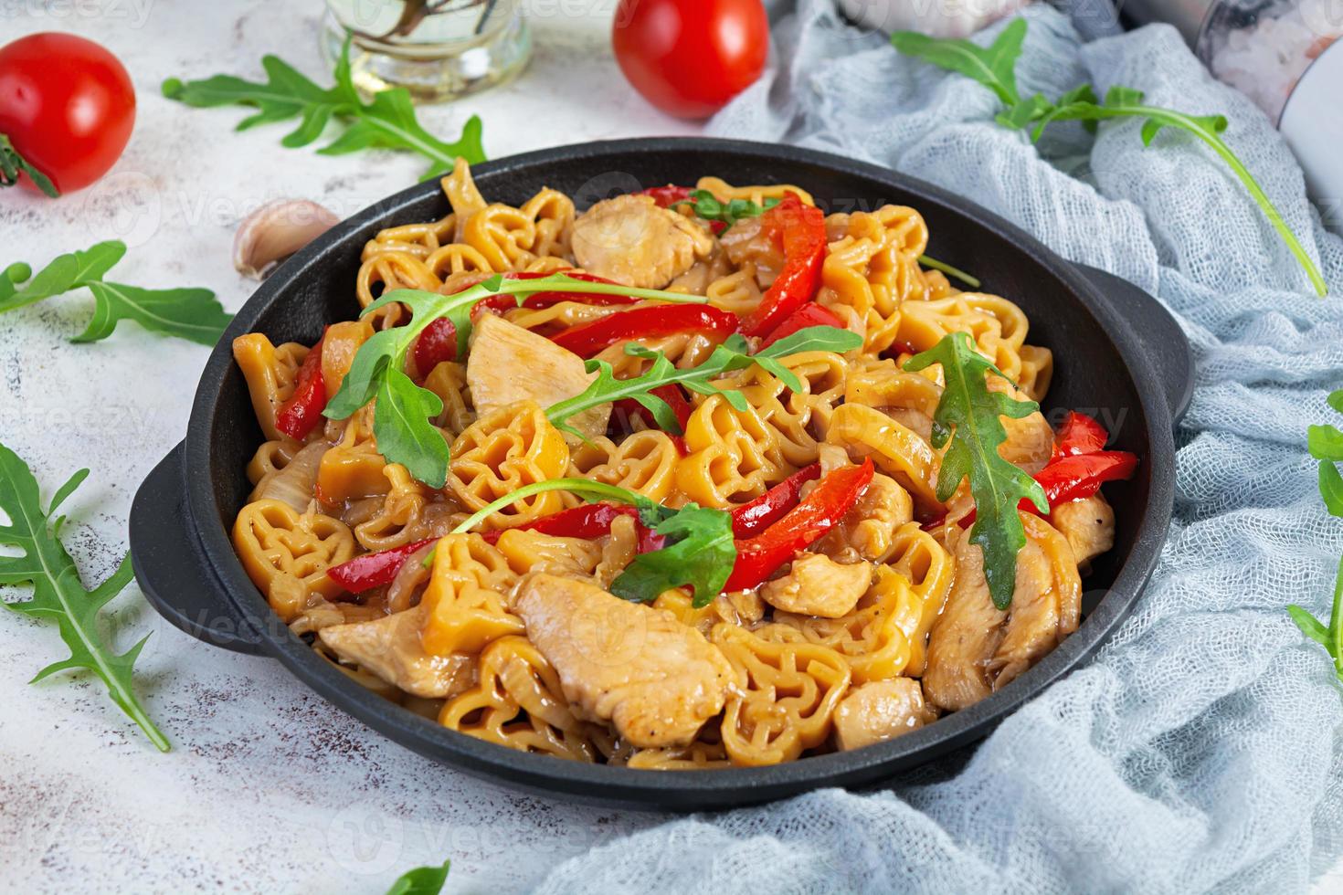 Tasty pasta in tomato sauce with chicken, pepper and herbs on white background photo