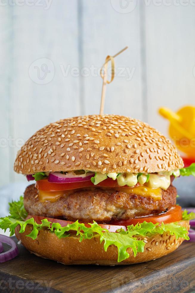 hamburguesa clásica casera con chuleta de ternera, queso, lechuga y tomate sobre fondo de madera foto