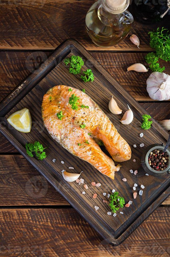 filete de salmón al horno con hierbas en tabla de cortar de madera. salmón a la plancha con sal y pimienta foto