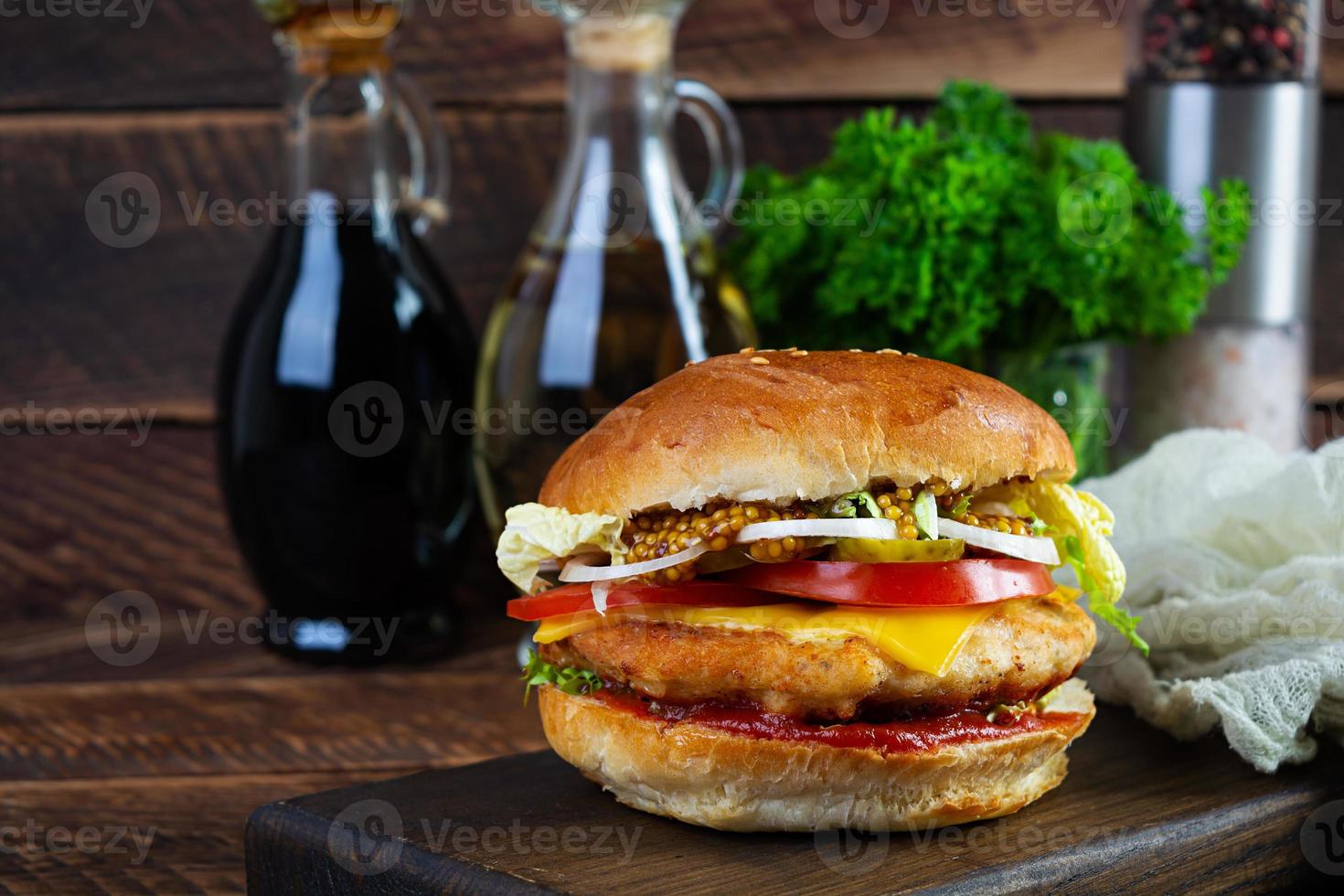 sabrosa hamburguesa de pollo con lechuga, queso, tomate y pepinillo. sándwich de comida rápida con chuleta de pollo foto