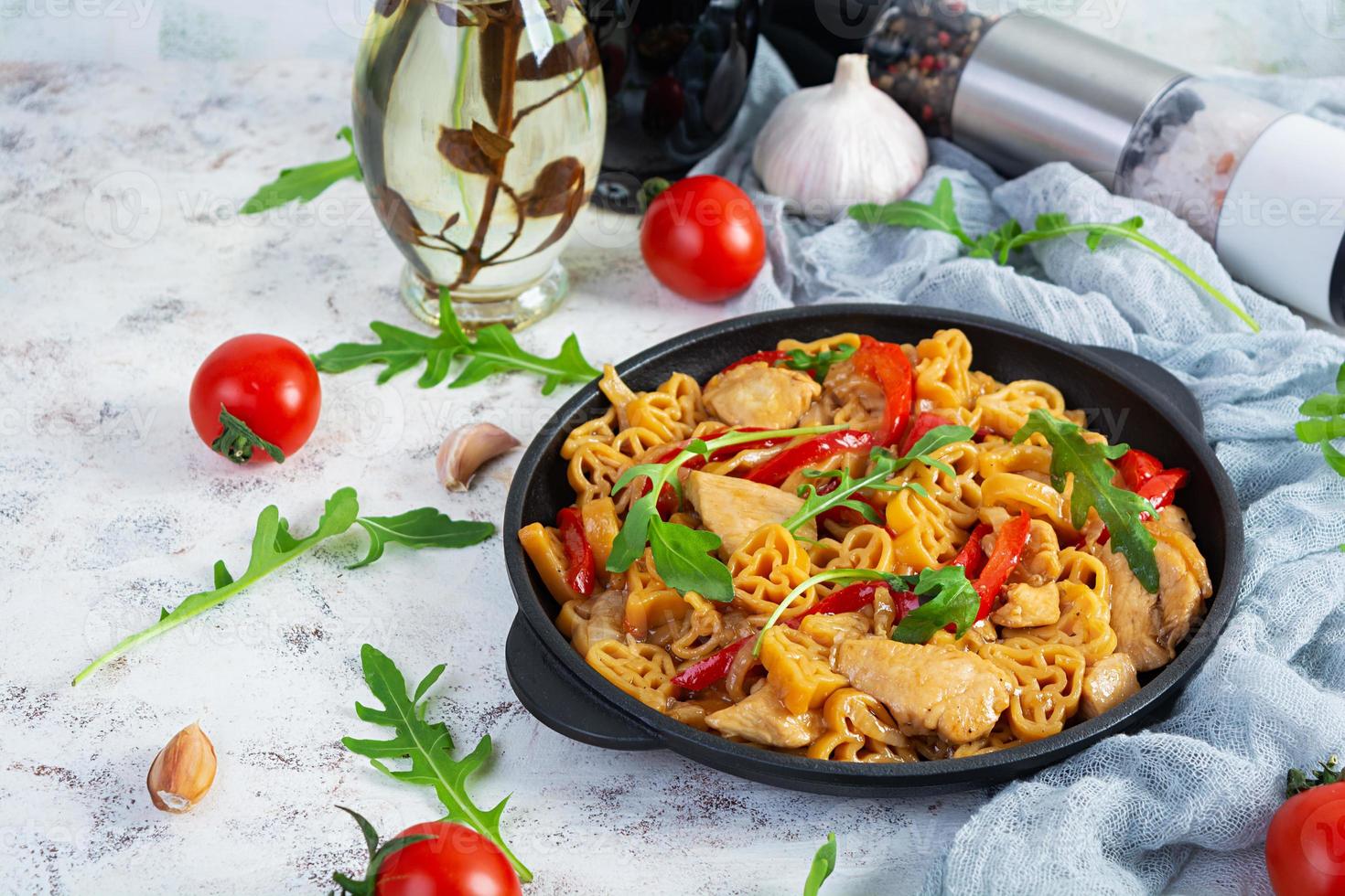 Tasty pasta in tomato sauce with chicken, pepper and herbs on white background photo