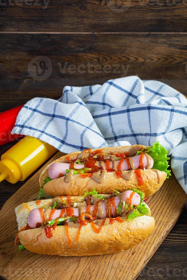 delicioso perrito caliente con ketchup y mostaza sobre fondo de madera. comida de la calle foto