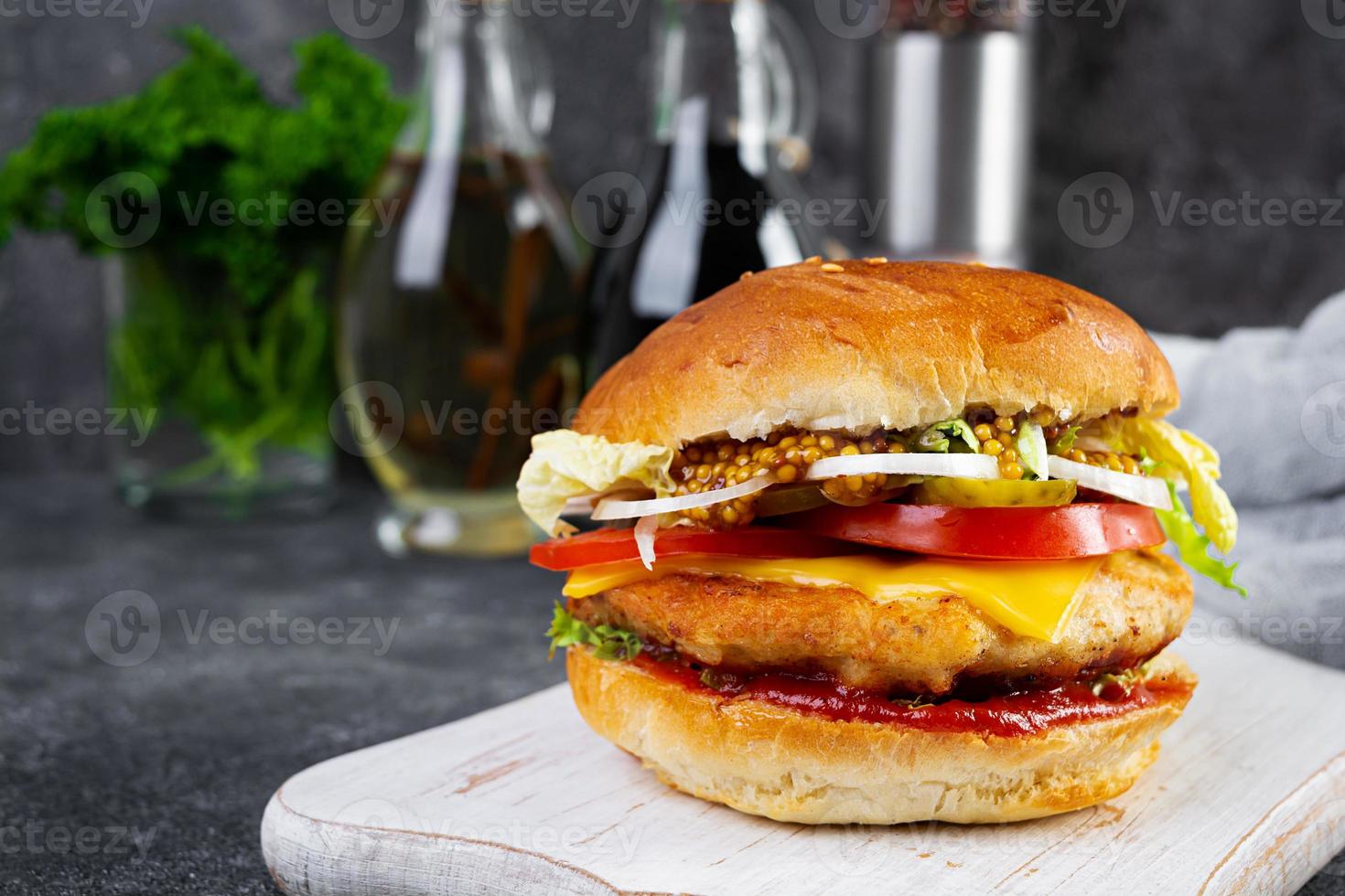 sabrosa hamburguesa de pollo con lechuga, queso, tomate y pepinillo. sándwich de comida rápida con chuleta de pollo foto