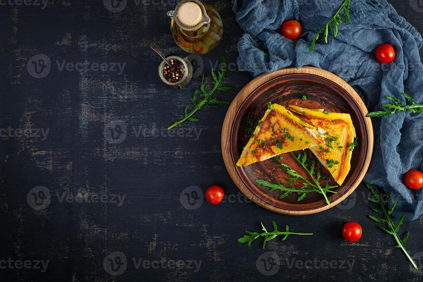 Roasted toast in scrambled eggs with ham, herbs and cheese cheddar. Delicious grilled breakfast sandwich photo