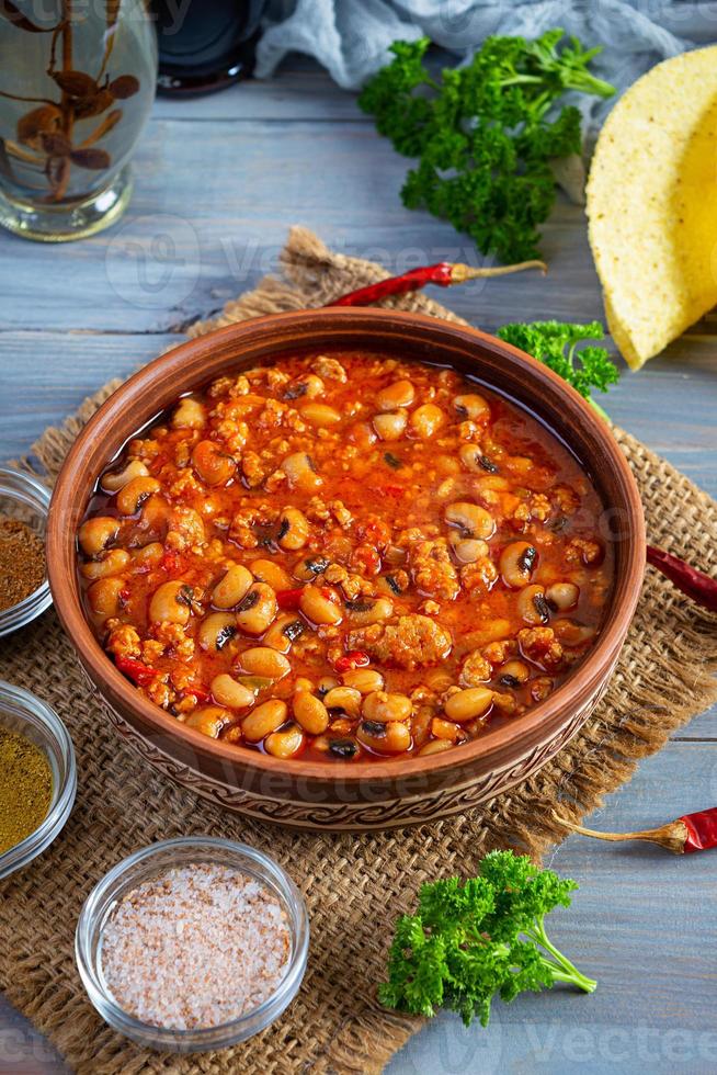 Chili con carne in a bowl on wooden background. Mexican cuisine photo