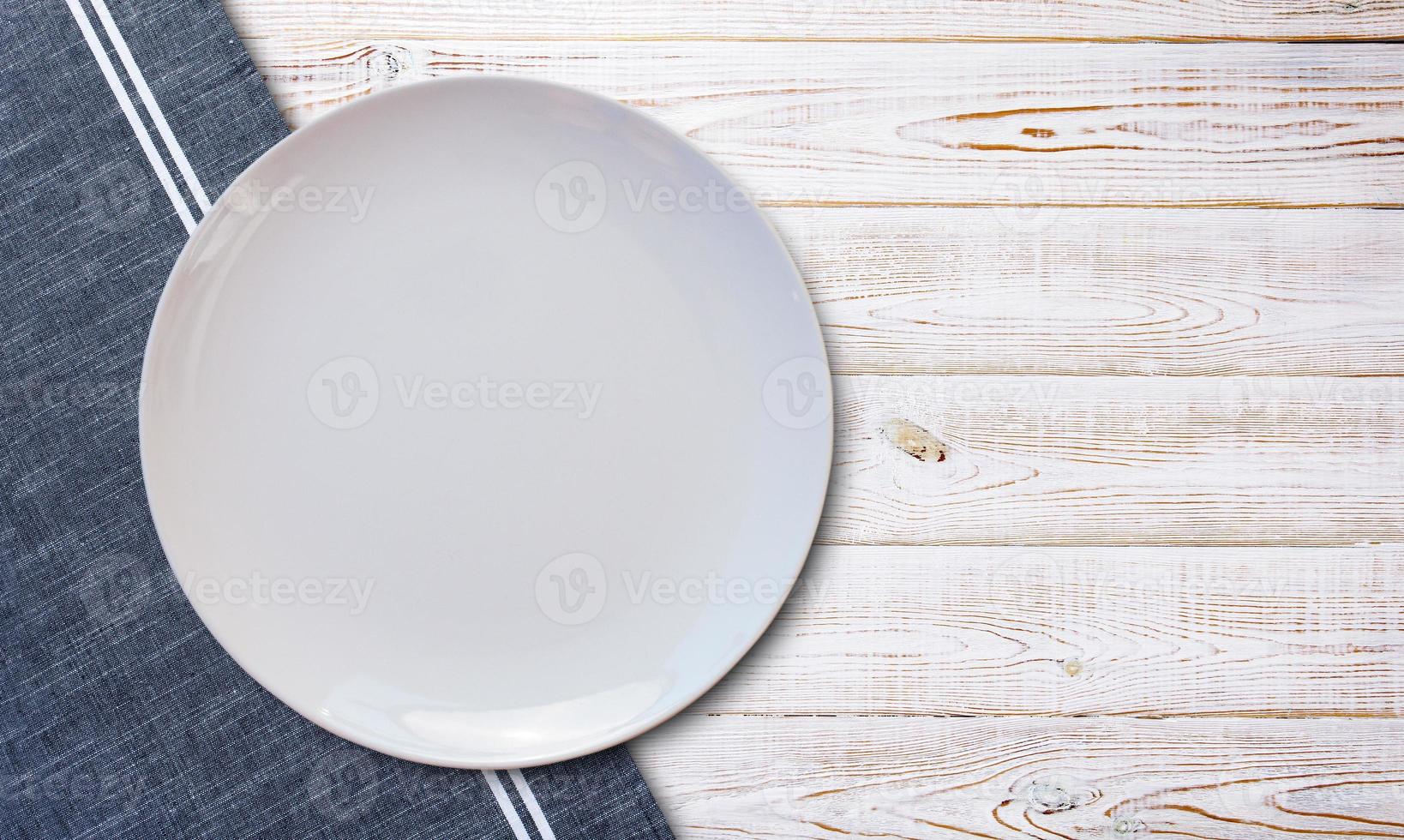 Empty white plate and napkin on light grey table, flat lay photo