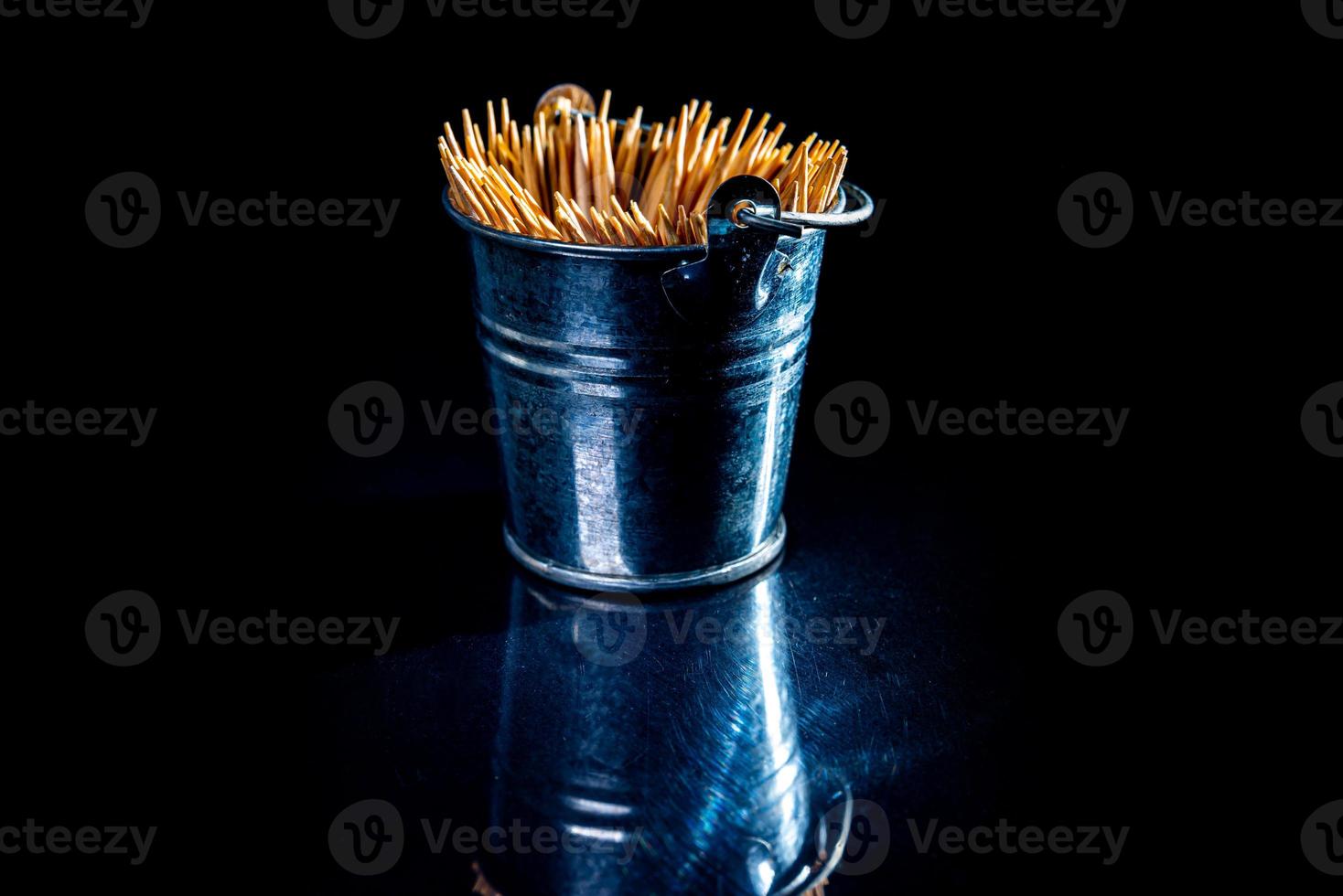 bamboo wooden toothpicks in glass jar, wine glass. in bucket. toothpicks on black background. front view toothpicks, dropped from hand, place for text, photo