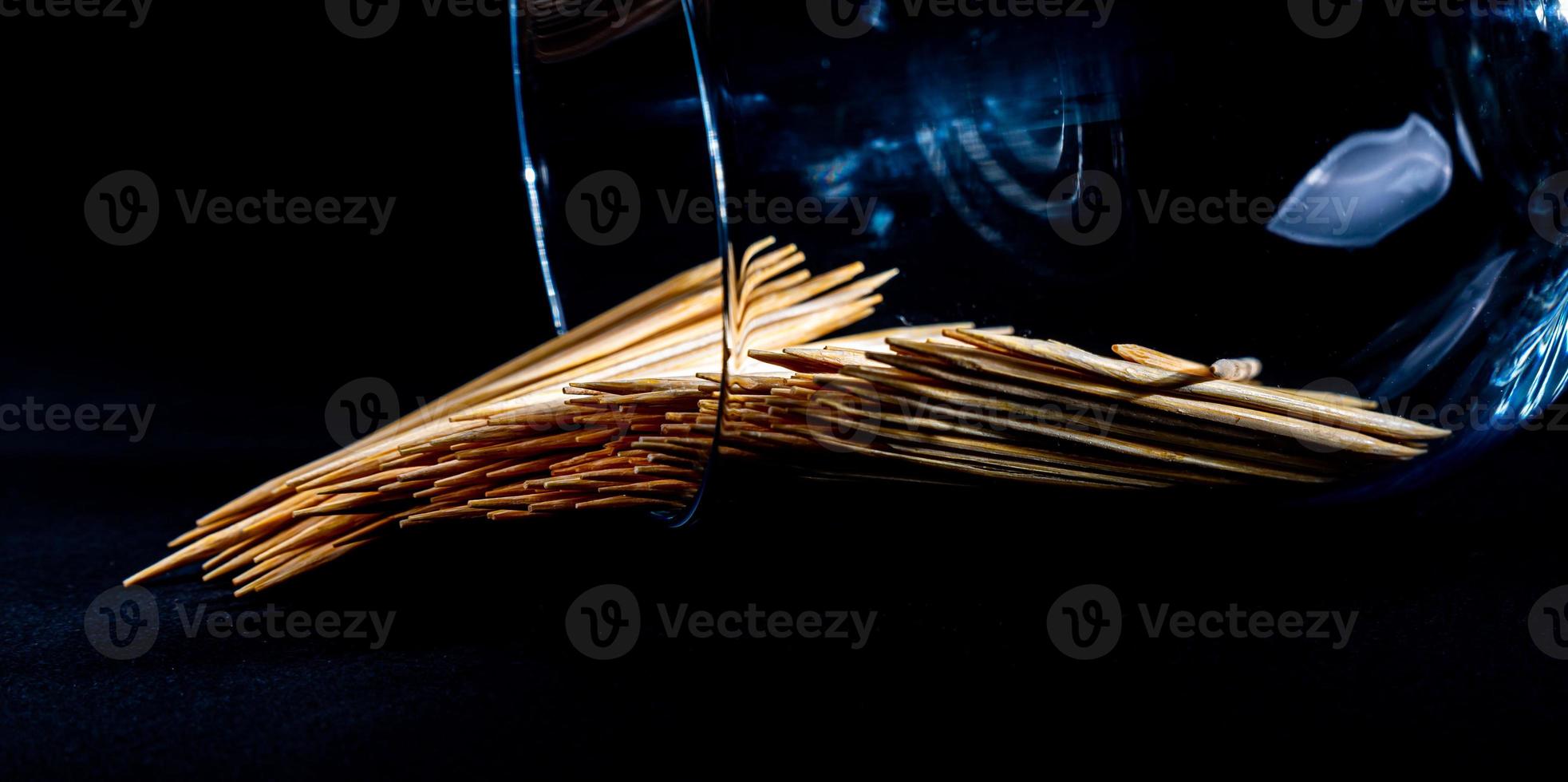 bamboo wooden toothpicks in glass jar, wine glass. in bucket. toothpicks on black background. front view toothpicks, dropped from hand, place for text, photo