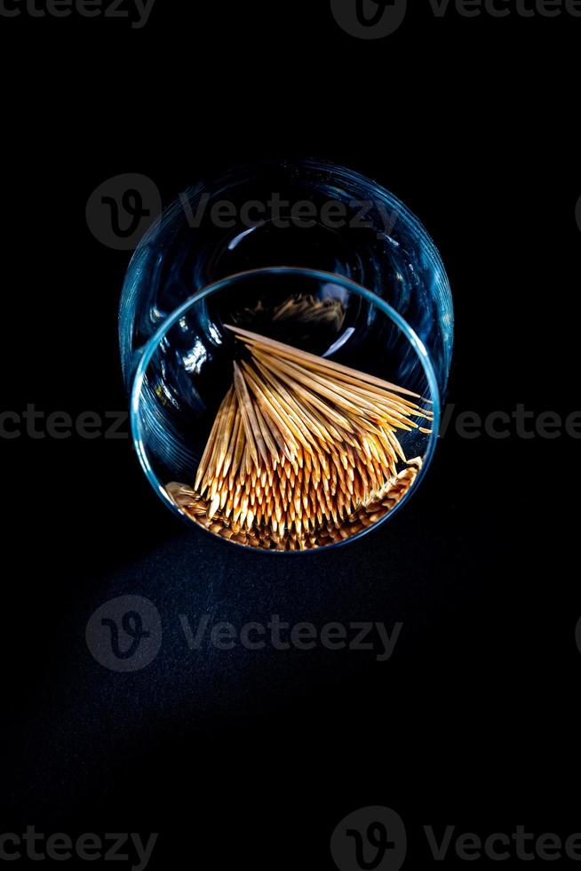 bamboo wooden toothpicks in glass jar, wine glass. in bucket. toothpicks on black background. front view toothpicks, dropped from hand, place for text, photo