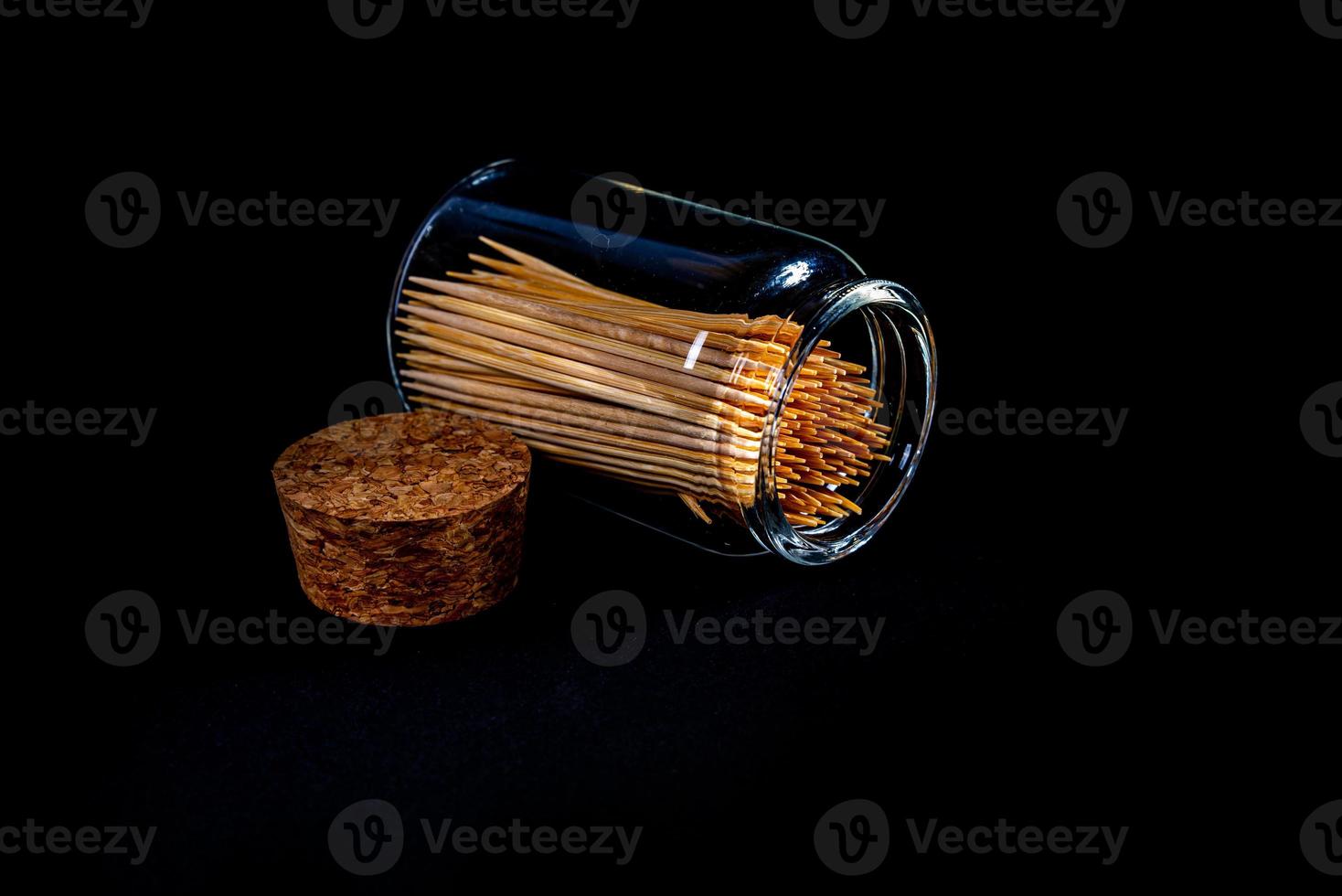 bamboo wooden toothpicks in glass jar, wine glass. in bucket. toothpicks on black background. front view toothpicks, dropped from hand, place for text, photo