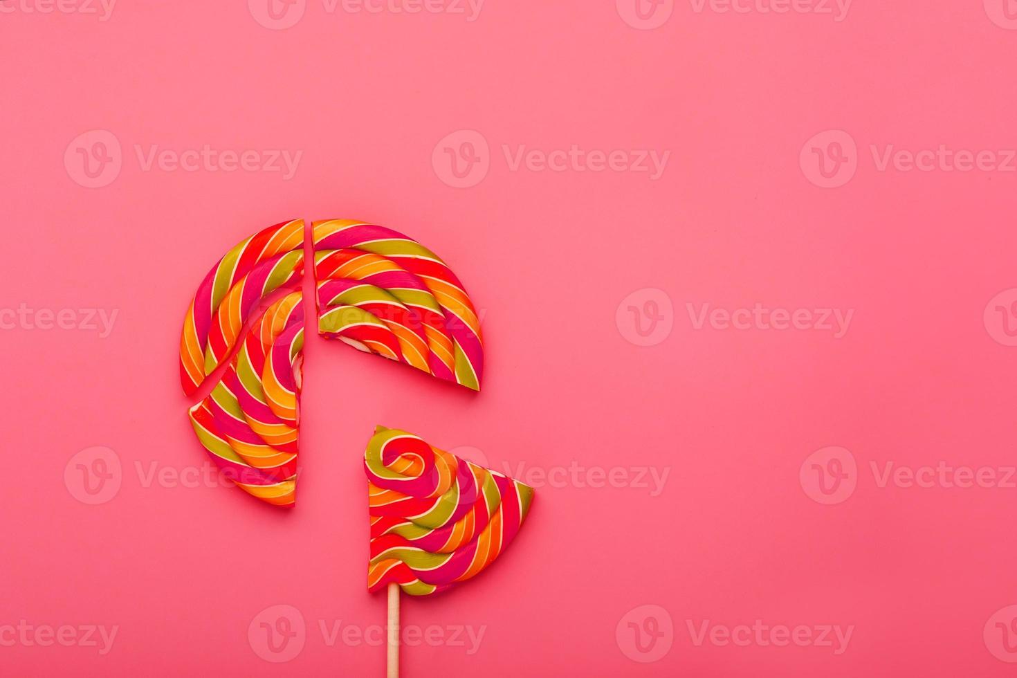 Lollipop broken into pieces on pink background, top view with copy space. photo