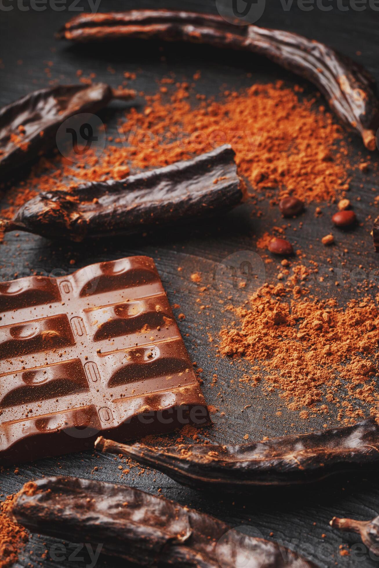 Carob chocolate and carob fruit powder on dark background. A tasty and