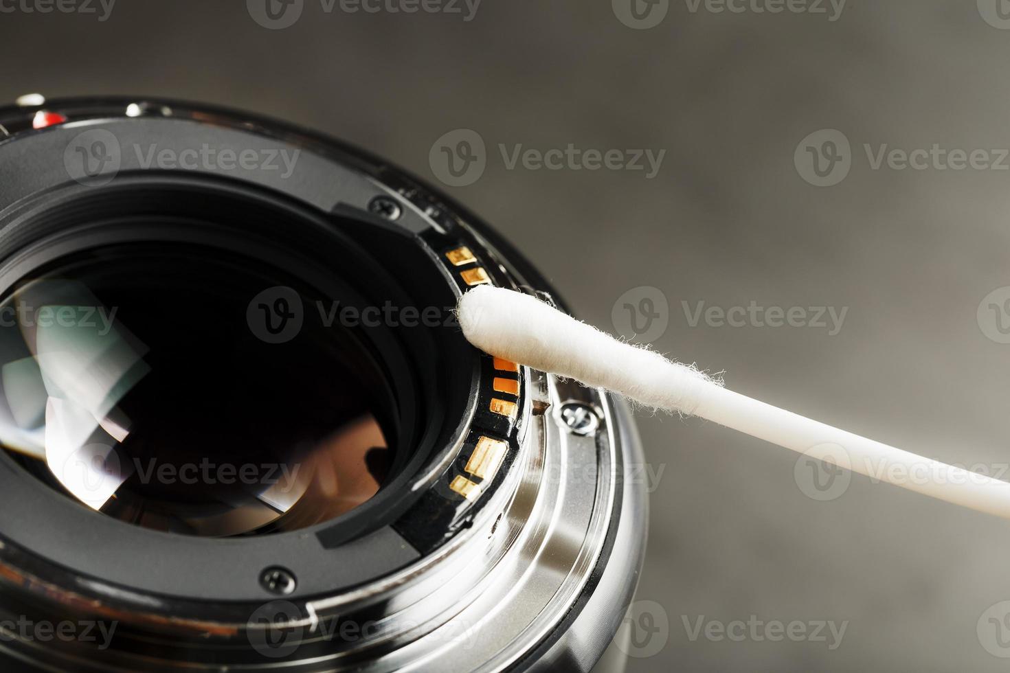 Gentle cleaning with a cotton swab camera Lens with a beautiful optical block close-up. photo