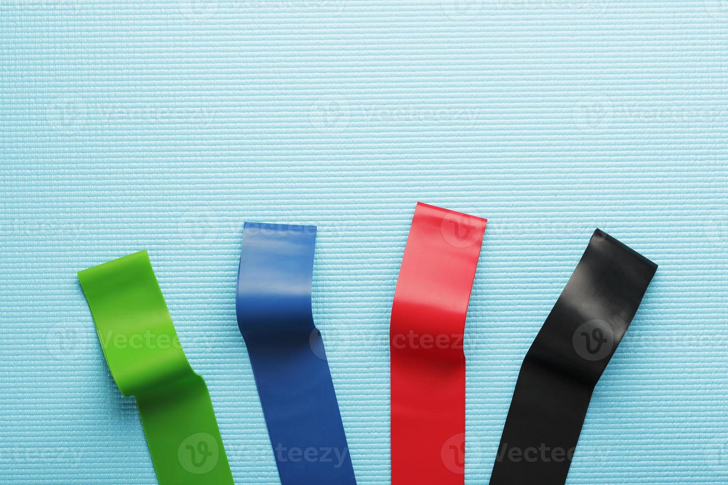 Fitness elastic bands of different colors and loads for sports on a blue background. photo