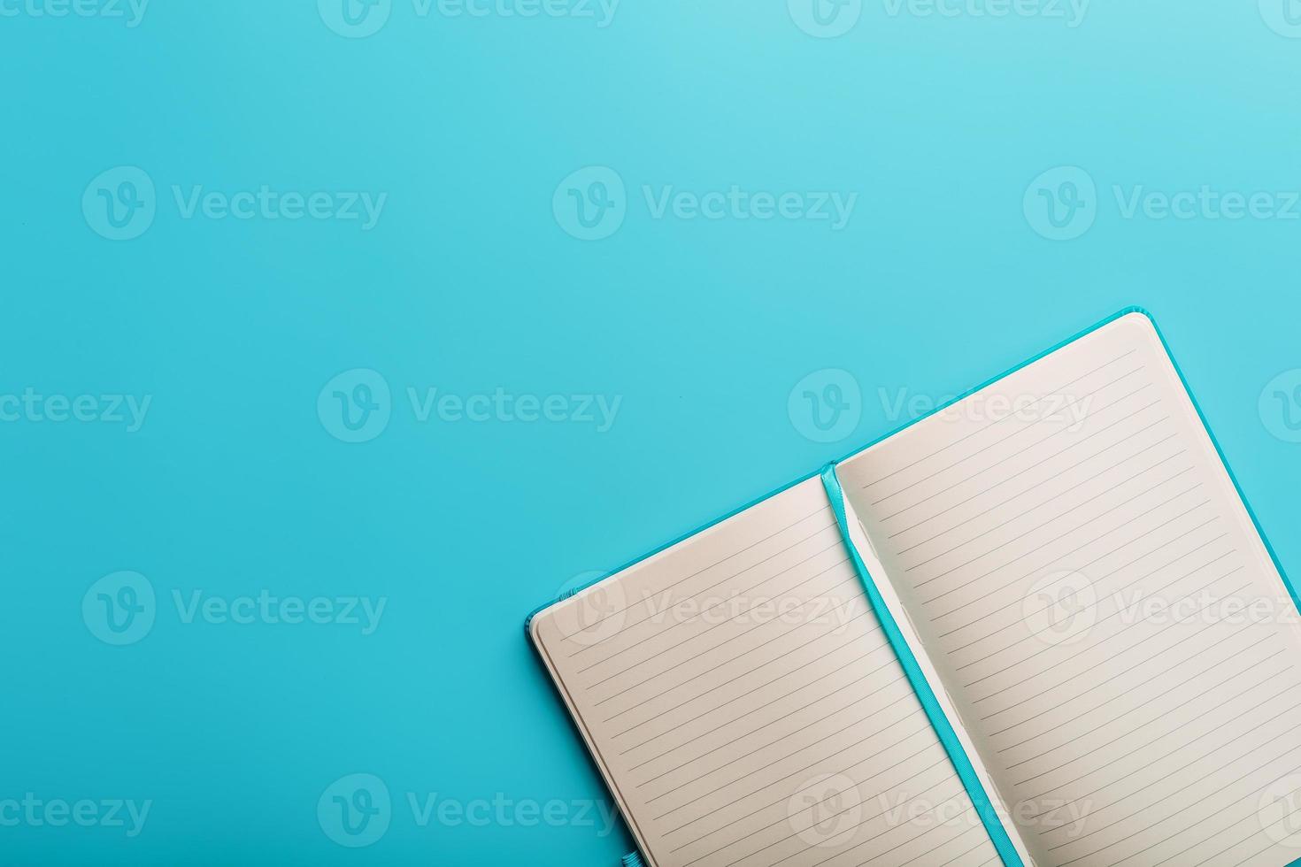cuaderno abierto, un libro con páginas en blanco y en blanco sobre un fondo azul, vista superior. foto
