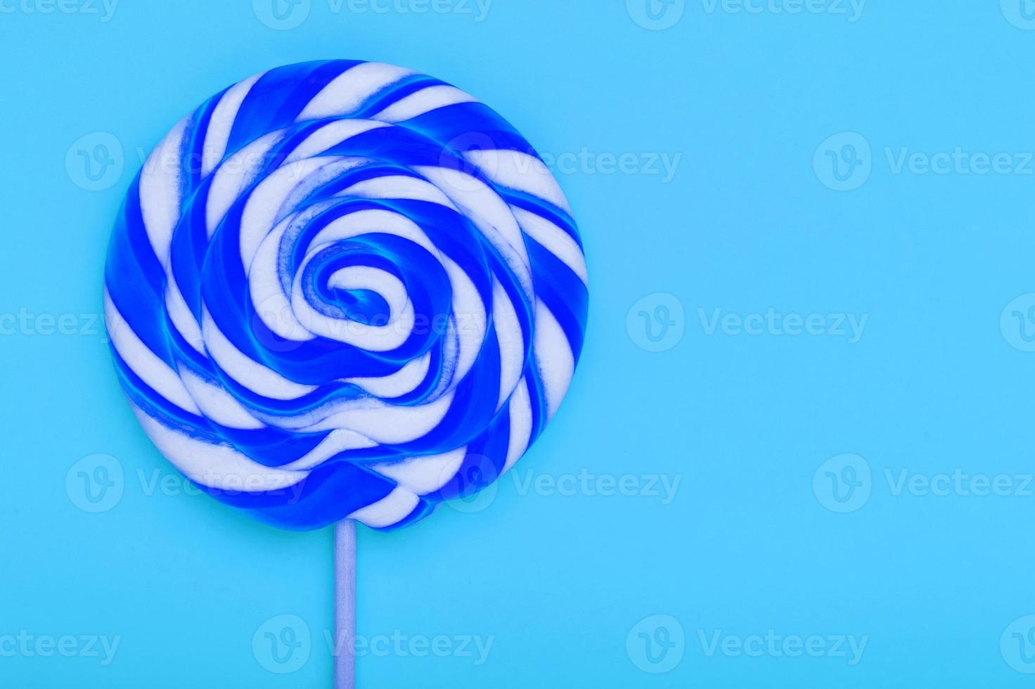 Blue round Lollipop on blue background. Minimal concept with copy space. photo