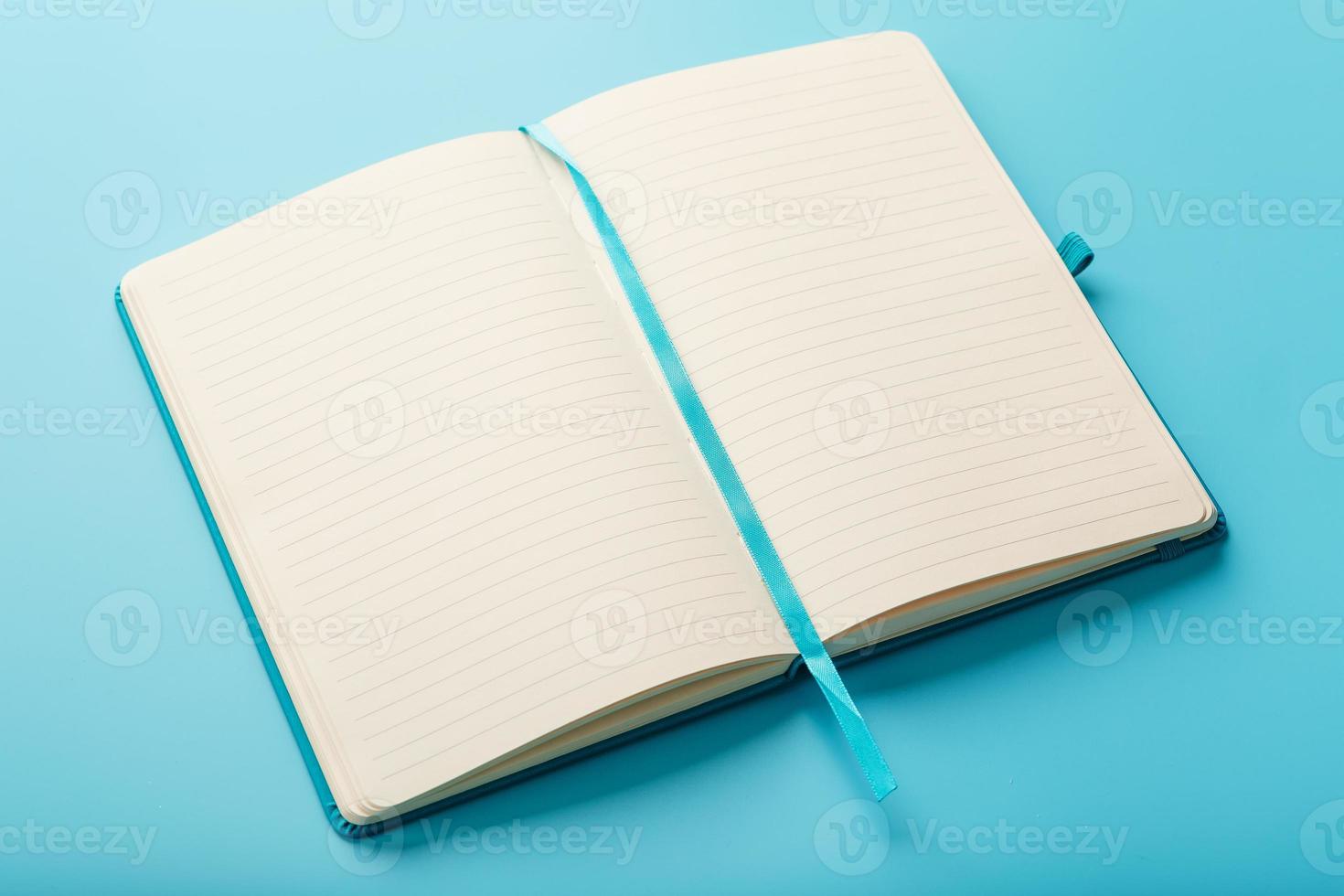 Open notebook, diary with blank and blank pages on a blue background, top view. photo