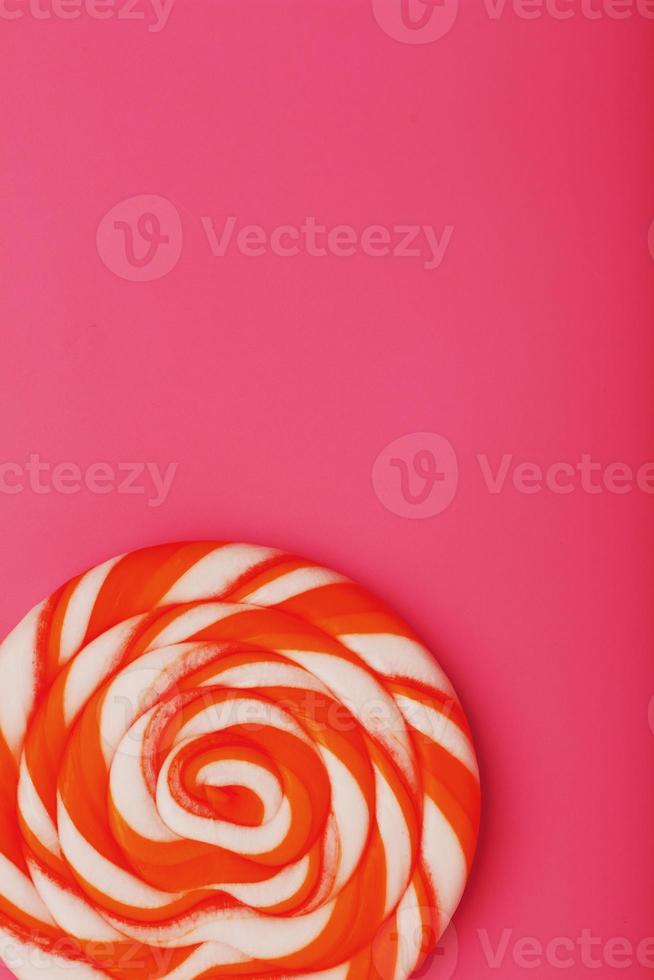 Orange Lollipop on a pink background with a soft contrast. Minimal concept with copy space. photo