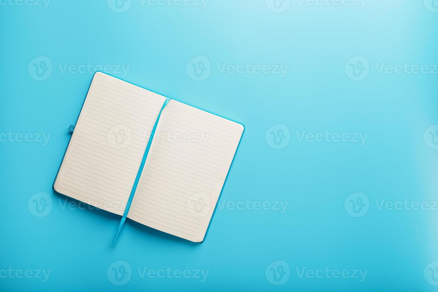 Open notebook, diary with blank and blank pages on a blue background, top view. photo