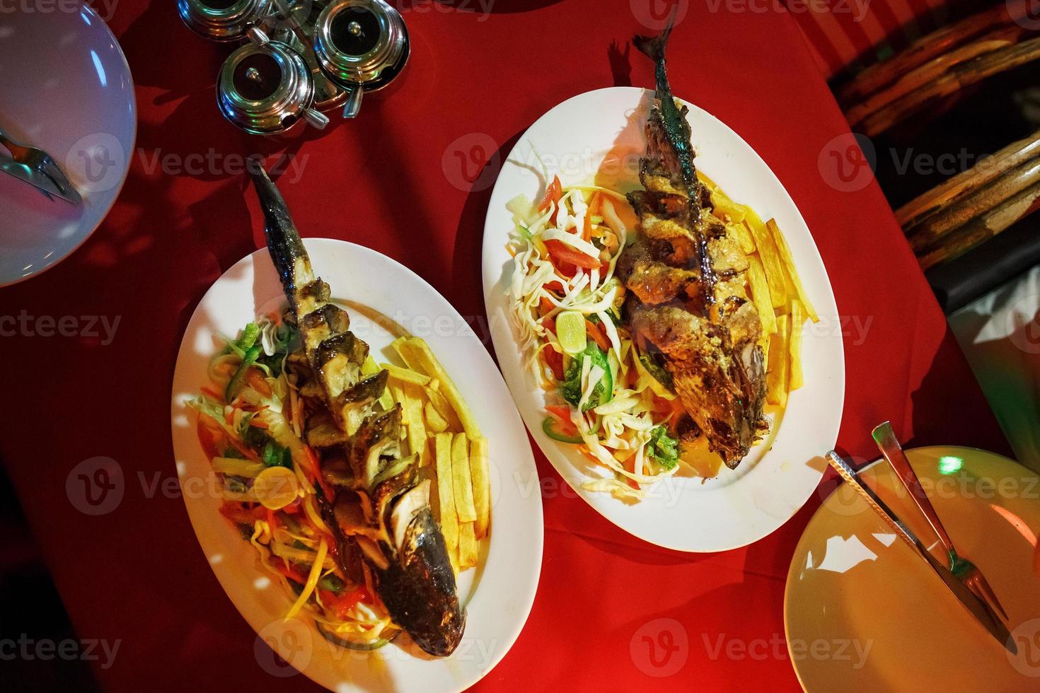 Fried fish with vegetables in a container on a red tablecloth, beautiful flow. Asian cuisine photo