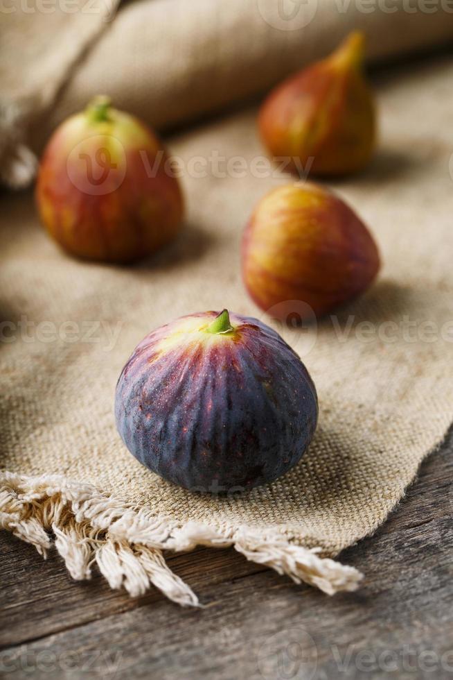 Ripe organic figs on the table. Group of purple and green figs on a farm wooden table with burlap cloth photo