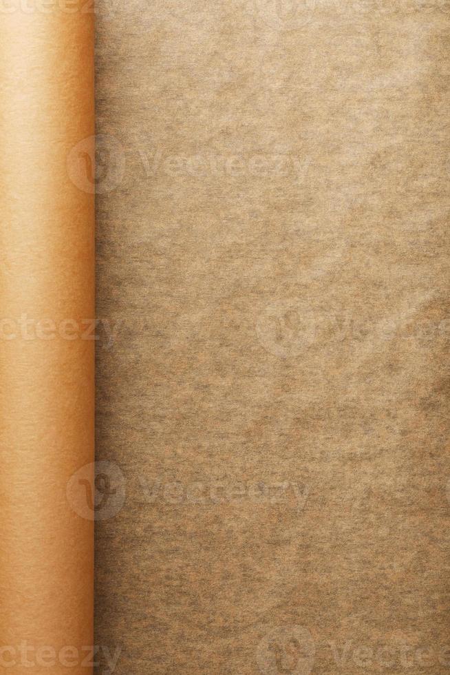 A roll of unfolded brown parchment paper, for baking food in on a dark background, top view. photo