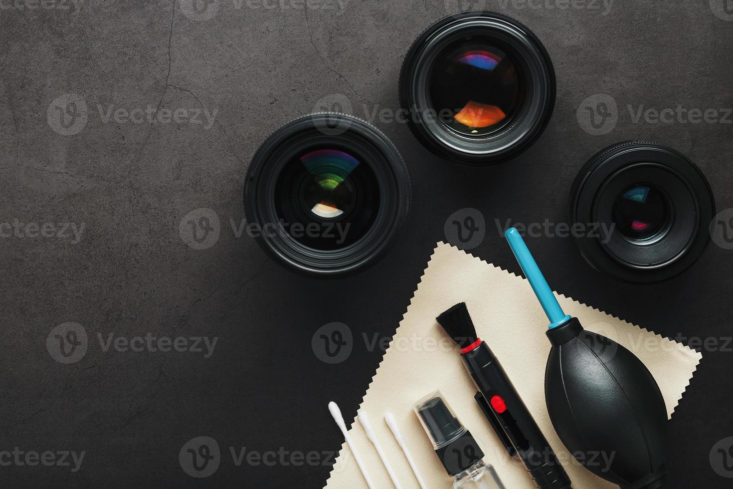 Tools for cleaning the camera with lenses on a dark textured background. photo