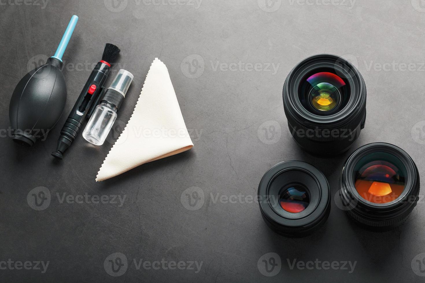 Tools for cleaning the camera with lenses on a dark textured background. photo