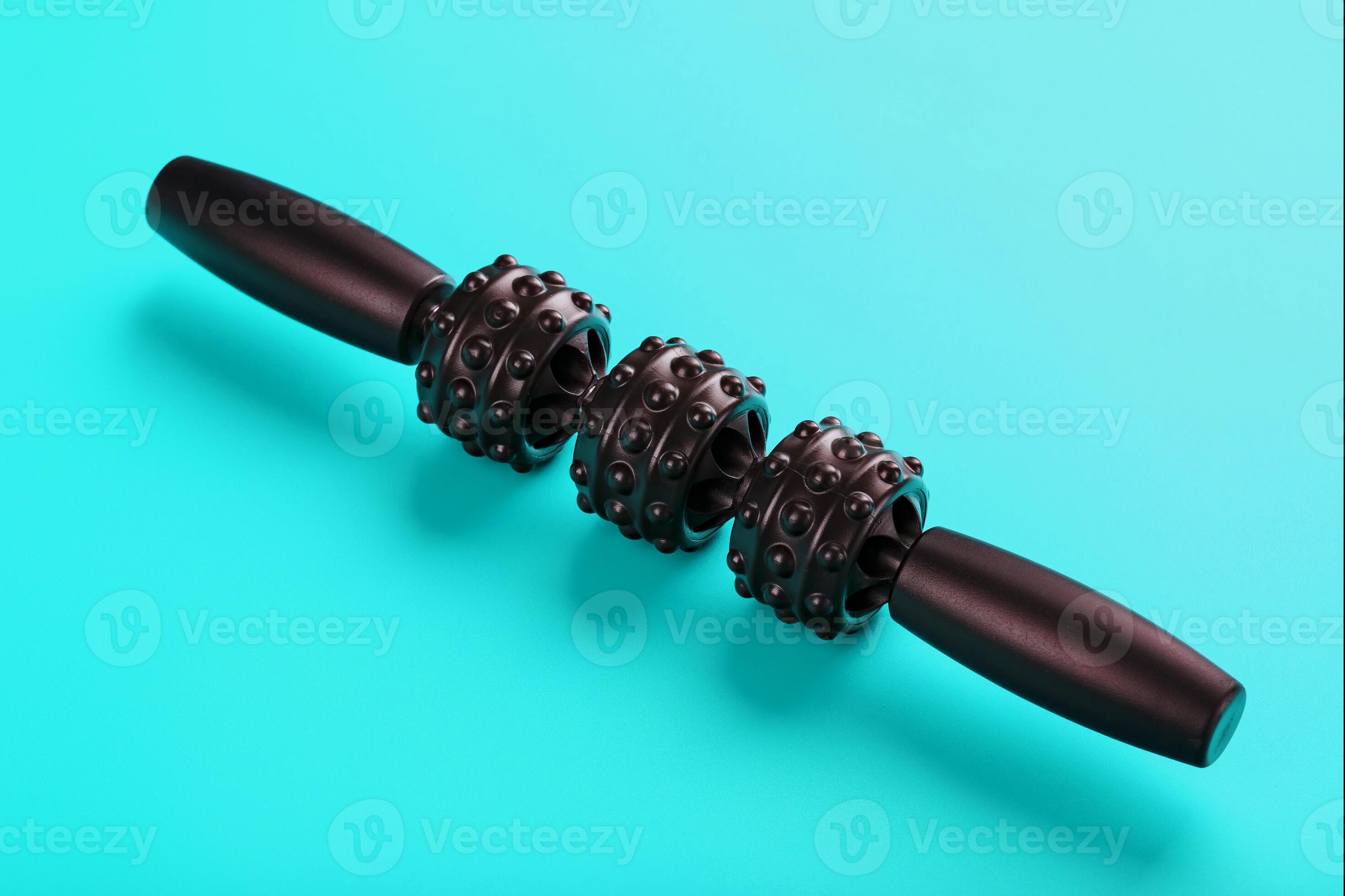 Black bumpy foam body massage roller on a blue background. 14595162