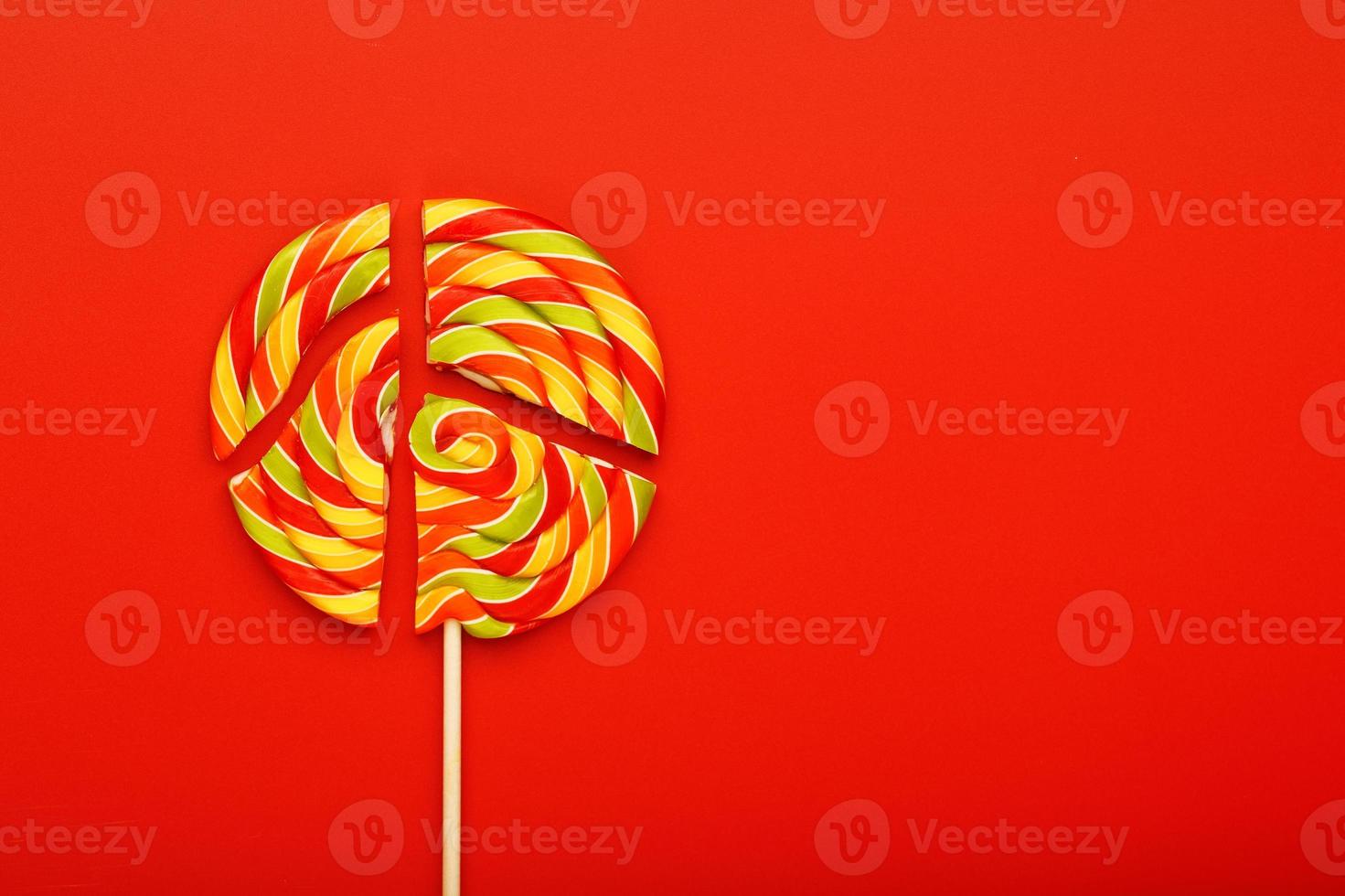 Lollipop broken into pieces on red background, top view with copy space. photo