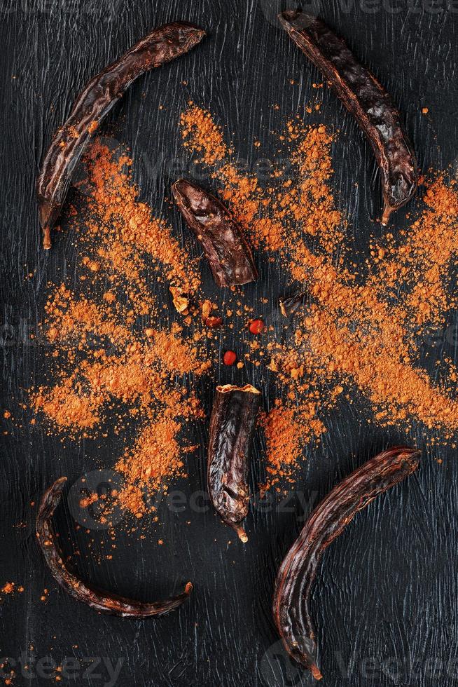 Carob carob fruit with powder on black background. Blast the Sweet powder from the pulp of the pods. photo