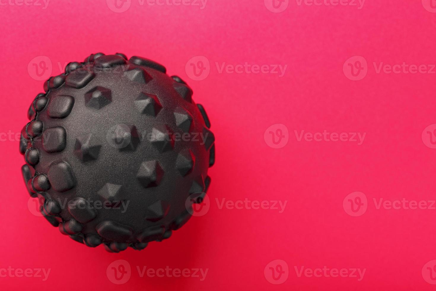 Black lumpy foam body massage ball on red background. photo