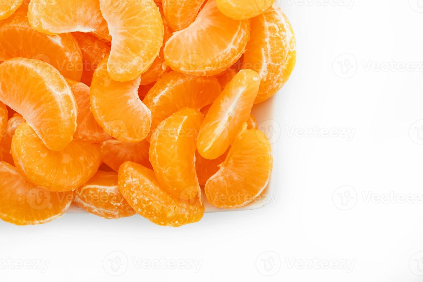 jugosas rodajas naranjas de mandarina en un plato blanco rectangular sobre un fondo blanco. aislar. foto