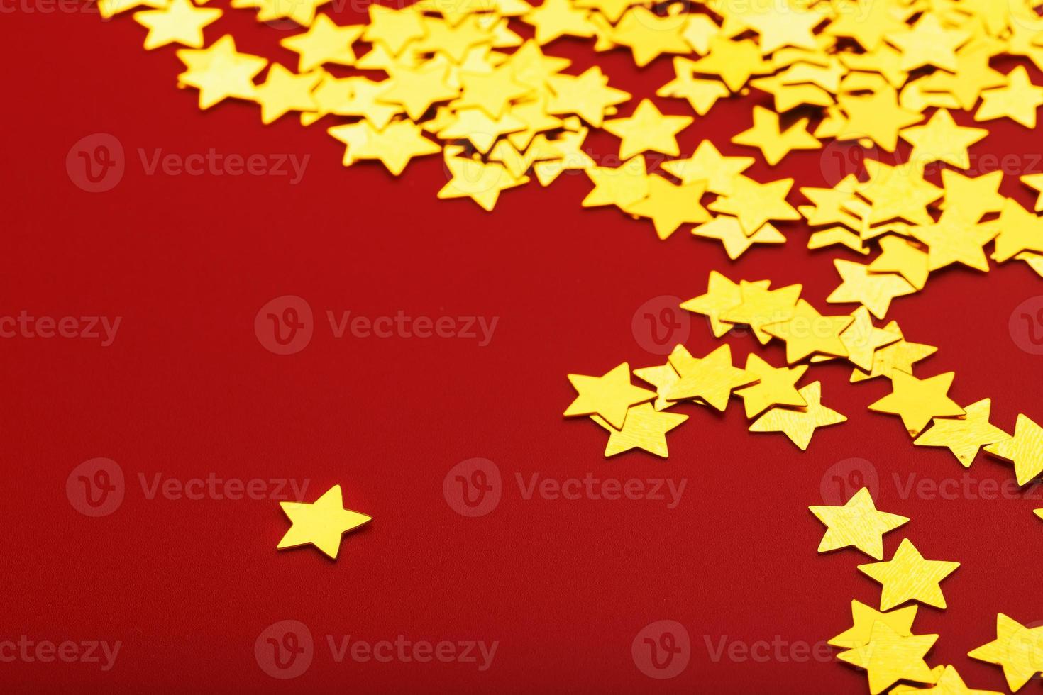 estrellas doradas sobre fondo rojo. el concepto de tarjetas de felicitación, titulares y sitio web. una dispersión de estrellas doradas foto