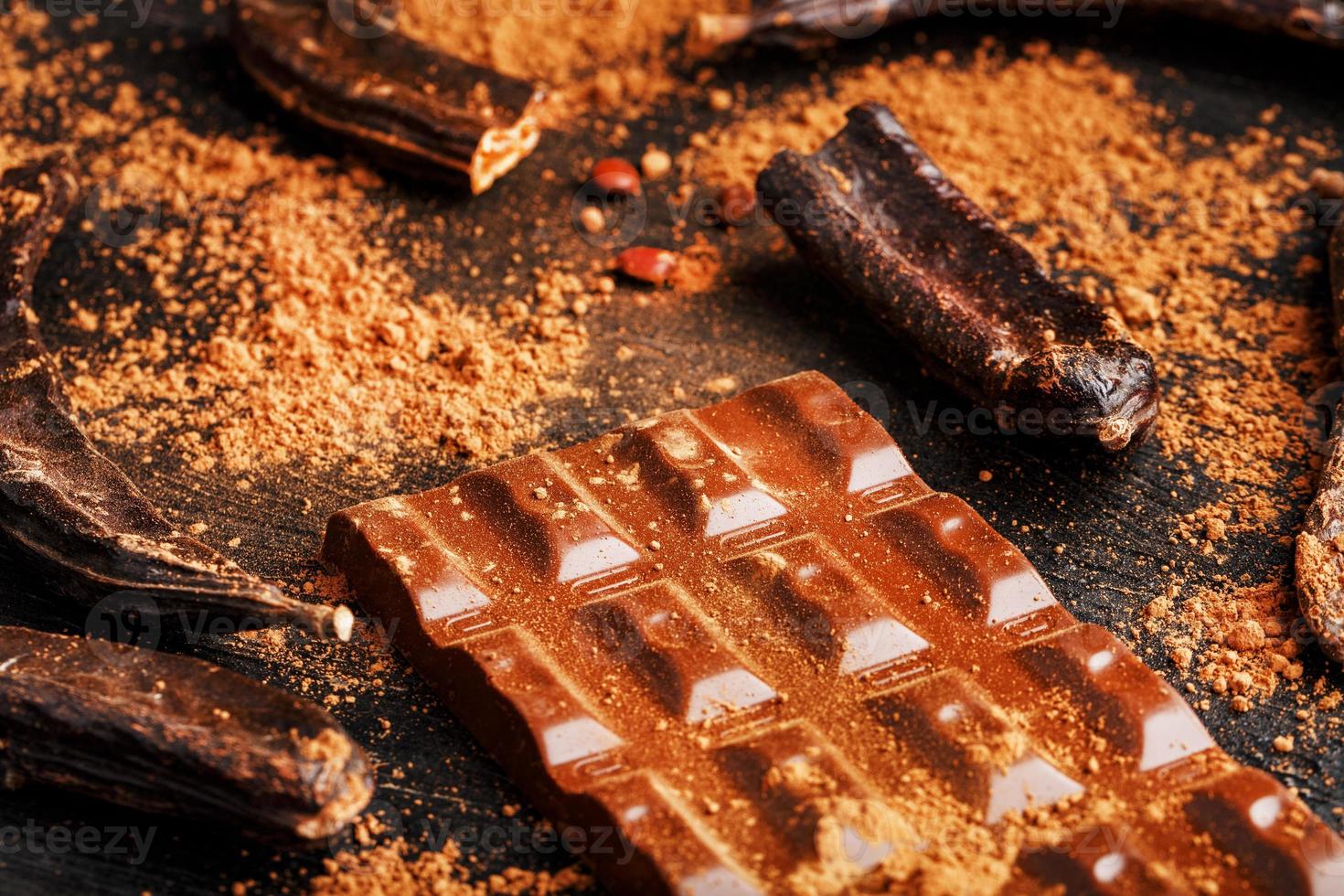 Carob chocolate and carob fruit powder on dark background. A tasty and useful substitute for chocolate. Health benefits. Soft contrast photo