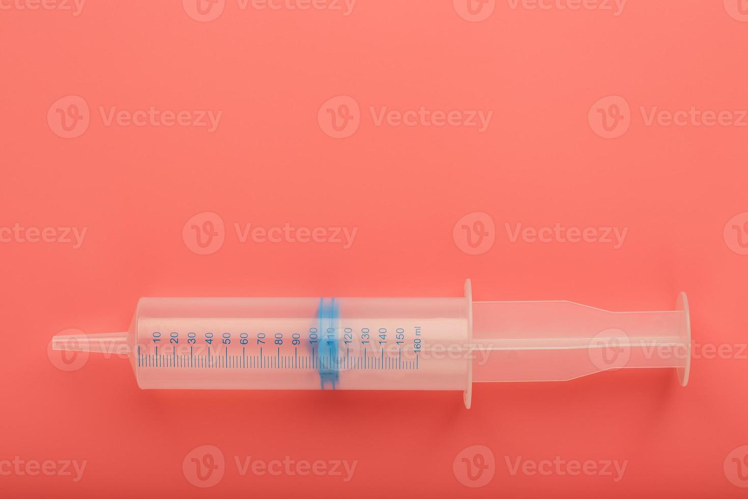 Large medical syringe on pink background with scale, copy space. photo