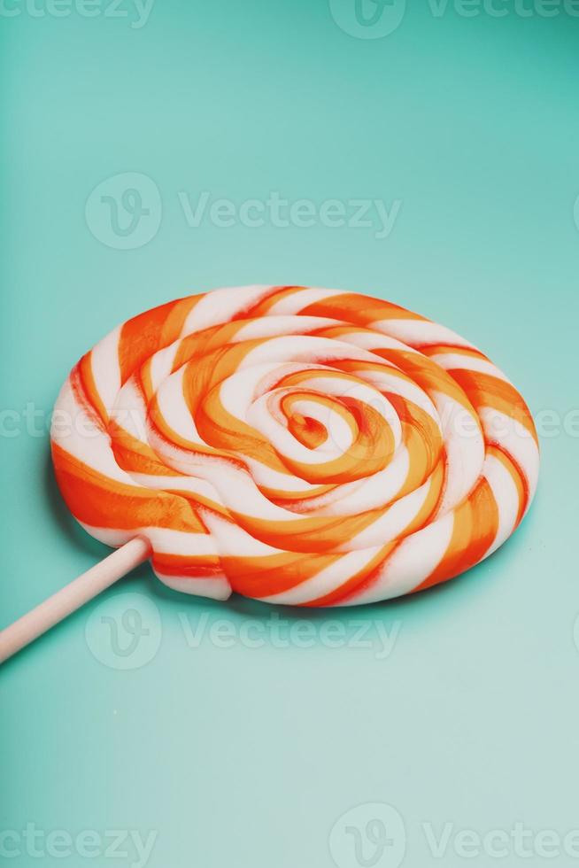 Orange Lollipop on blue background with soft contrast. Minimal concept with copy space. photo