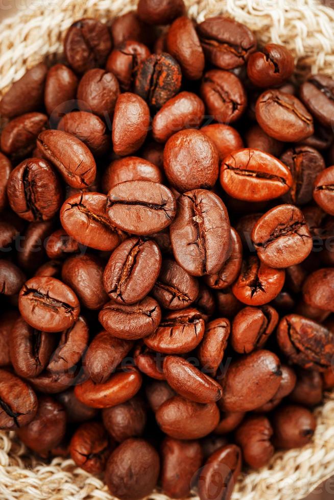 Freshly roasted aromatic coffee in a burlap bag on a wooden background. photo