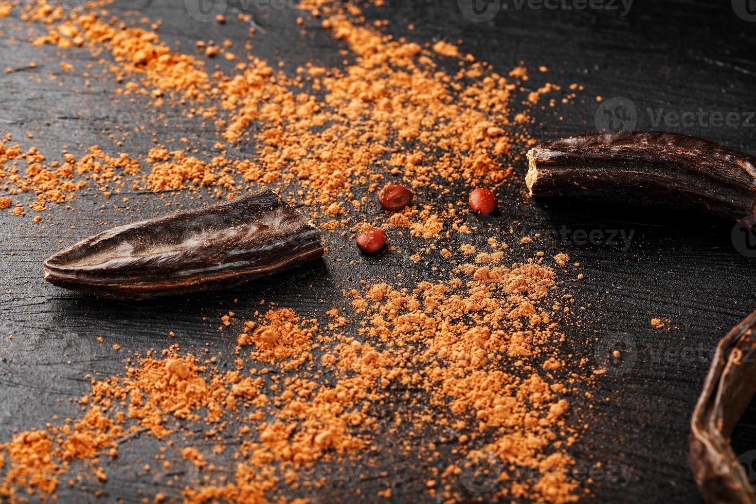 Carob carob fruit with powder on black background. Blast the Sweet powder from the pulp of the pods. photo