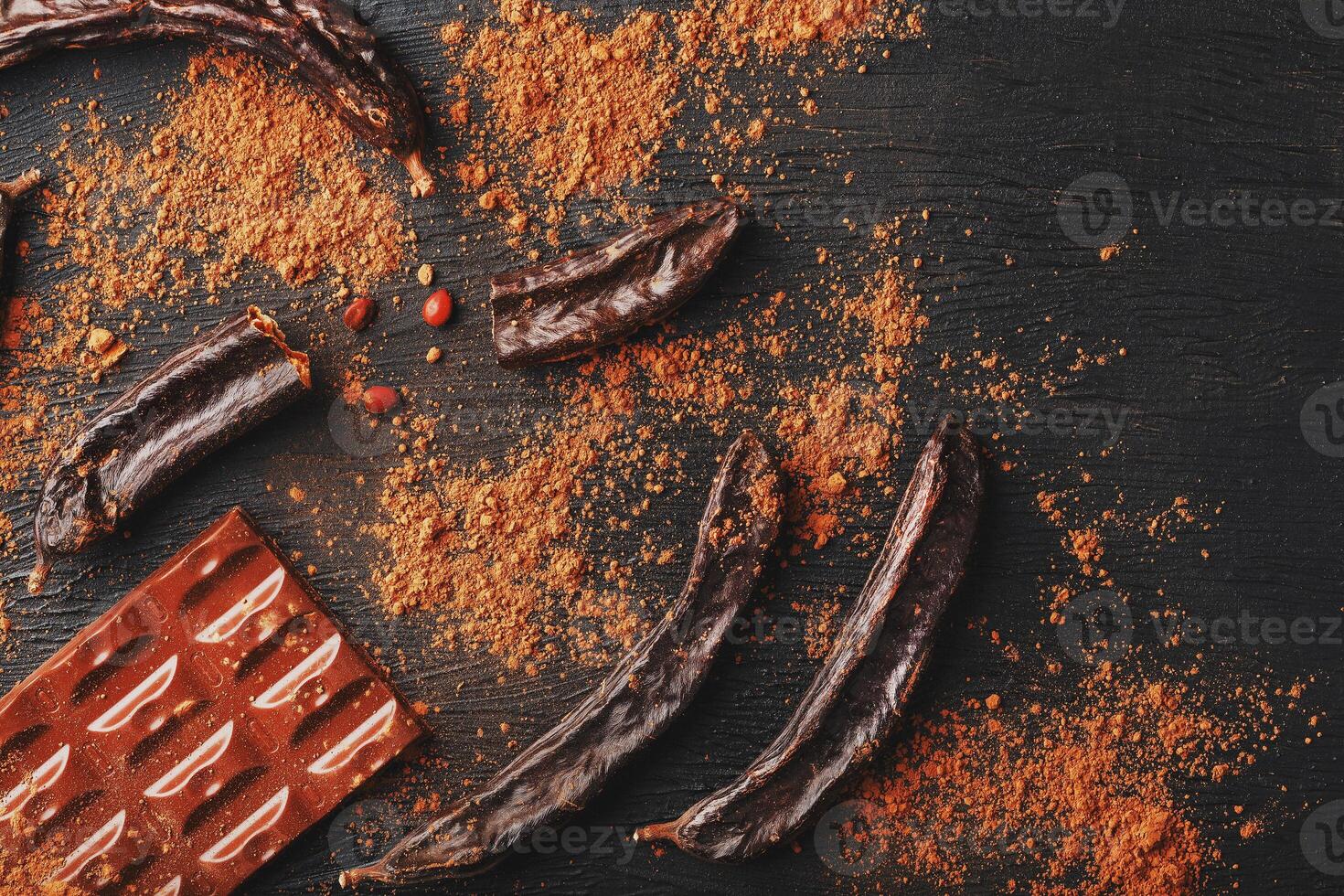 Carob chocolate and carob fruit powder on dark background. A tasty and