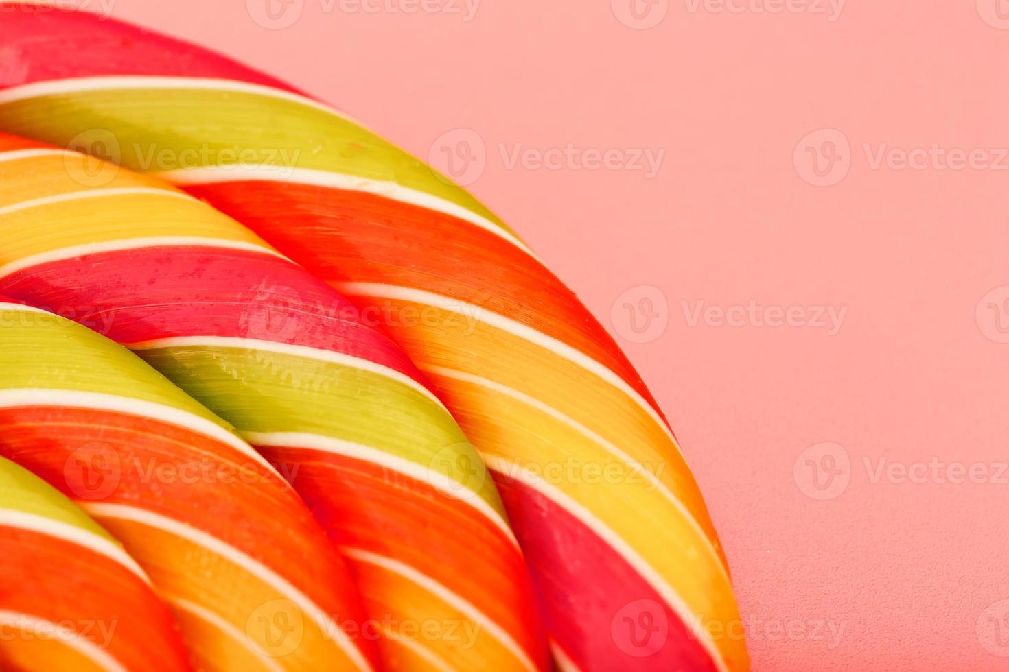 Lollipop multicolored close-up as background texture on pieces on pink background. photo