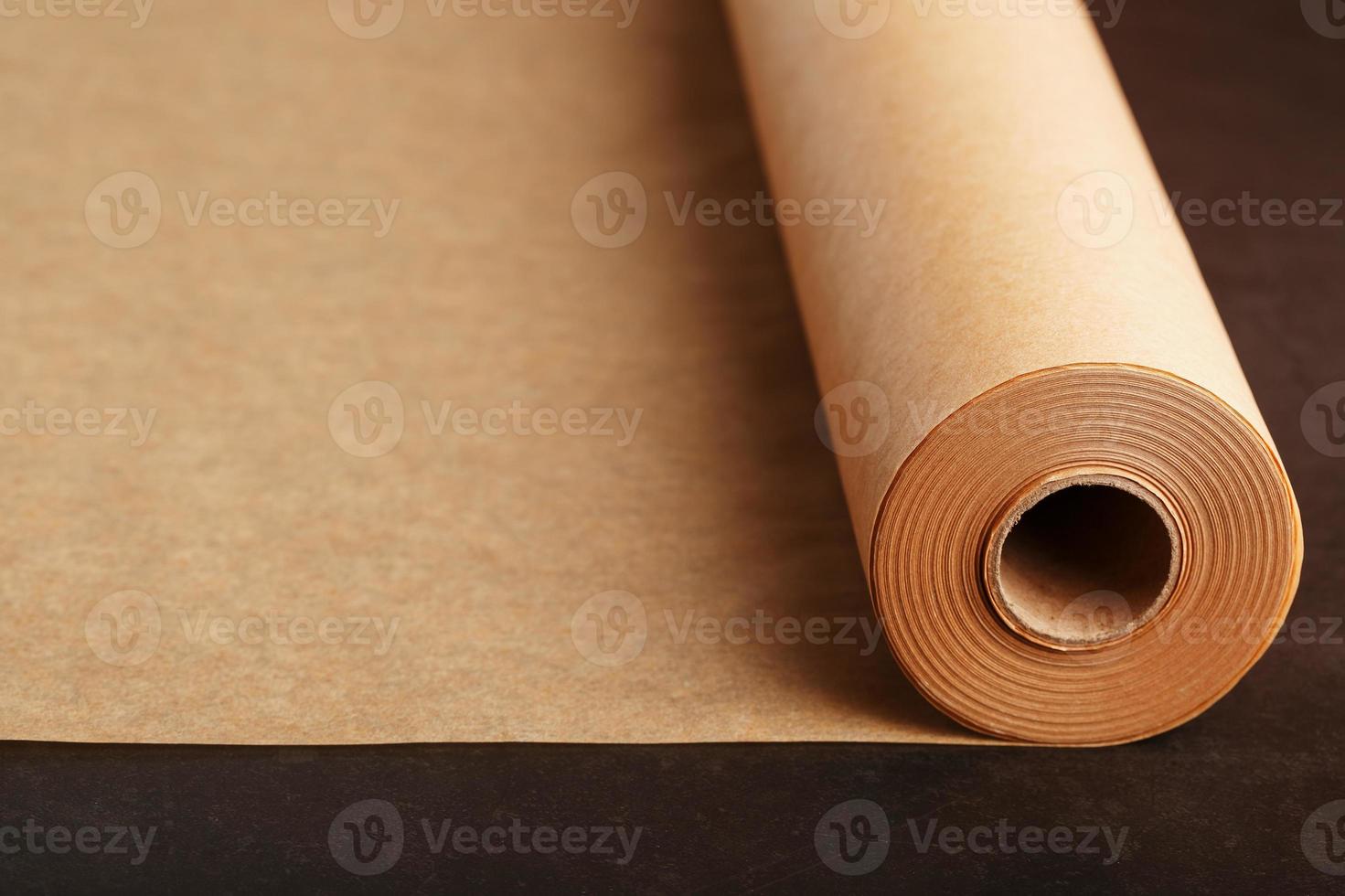 A roll of unfolded brown parchment paper, for baking food in on a dark background, top view. photo