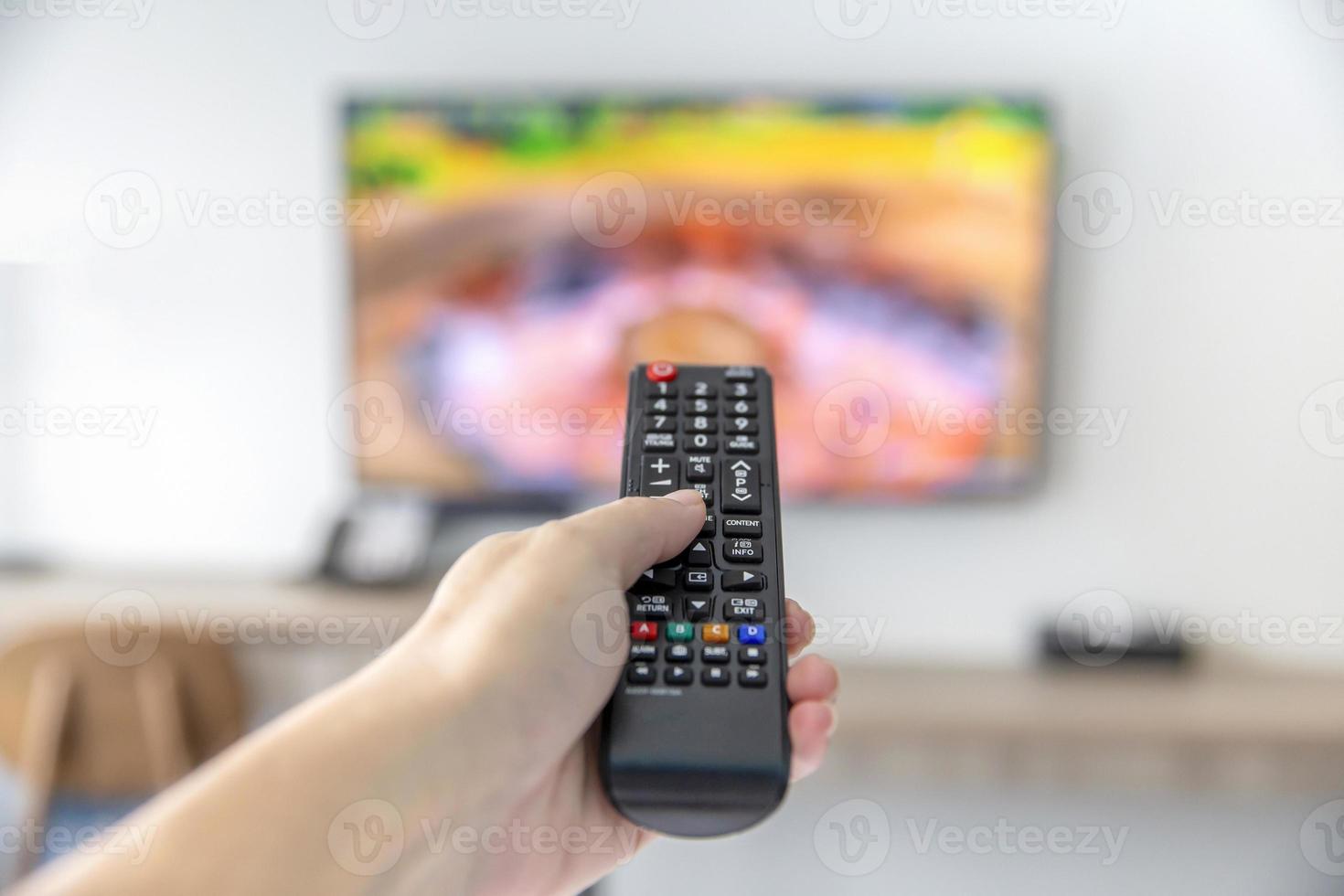 The man with the remote control watching TV and using remote controller and presses the button photo