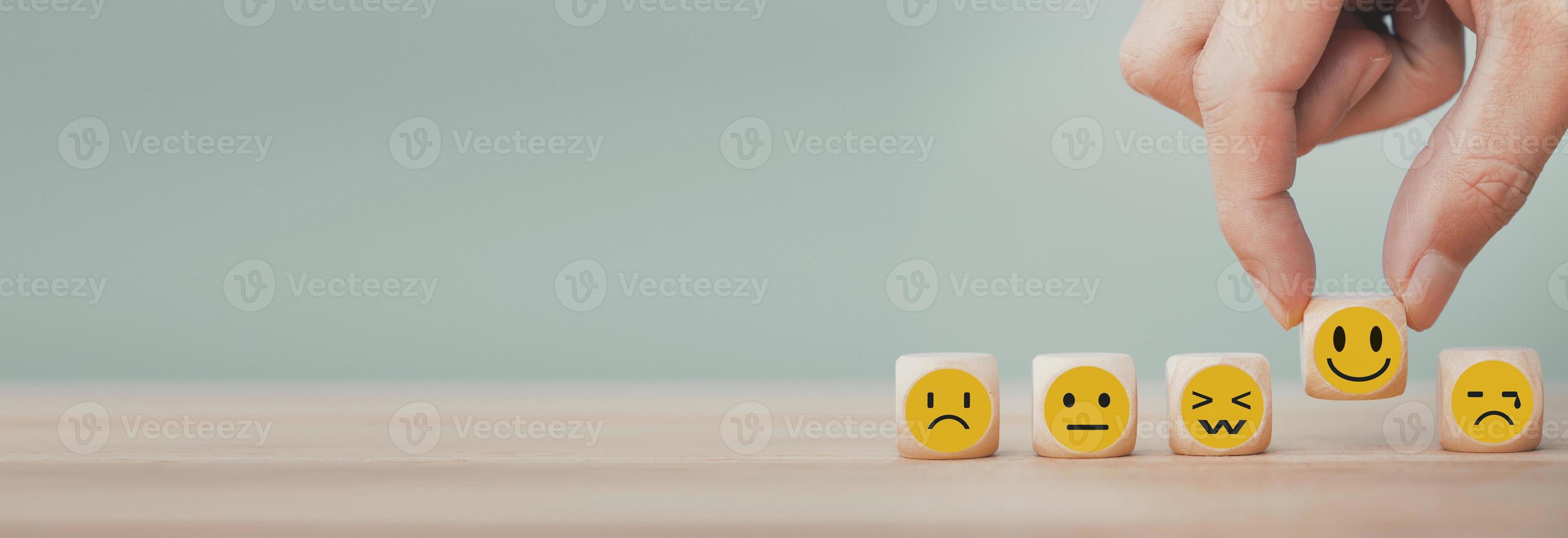 Hand chooses with happy smile face emoticon icons on Wooden Cube , good feedback rating for customer review survey photo