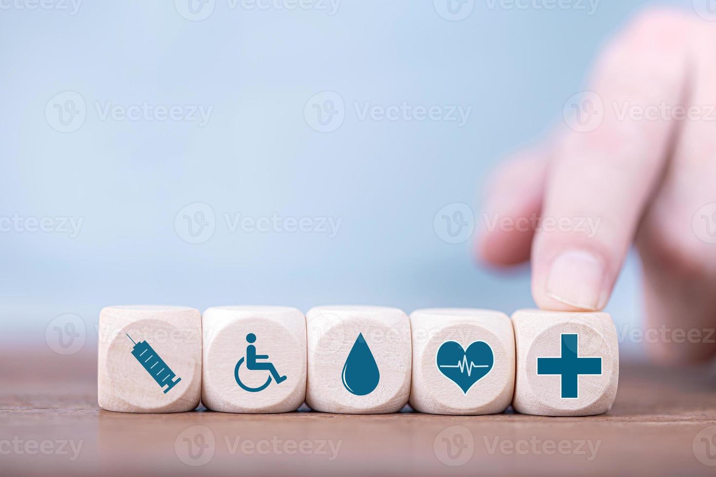 Businessman chooses a emoticon icons healthcare medical symbol on wooden block , Healthcare and medical Insurance concept photo