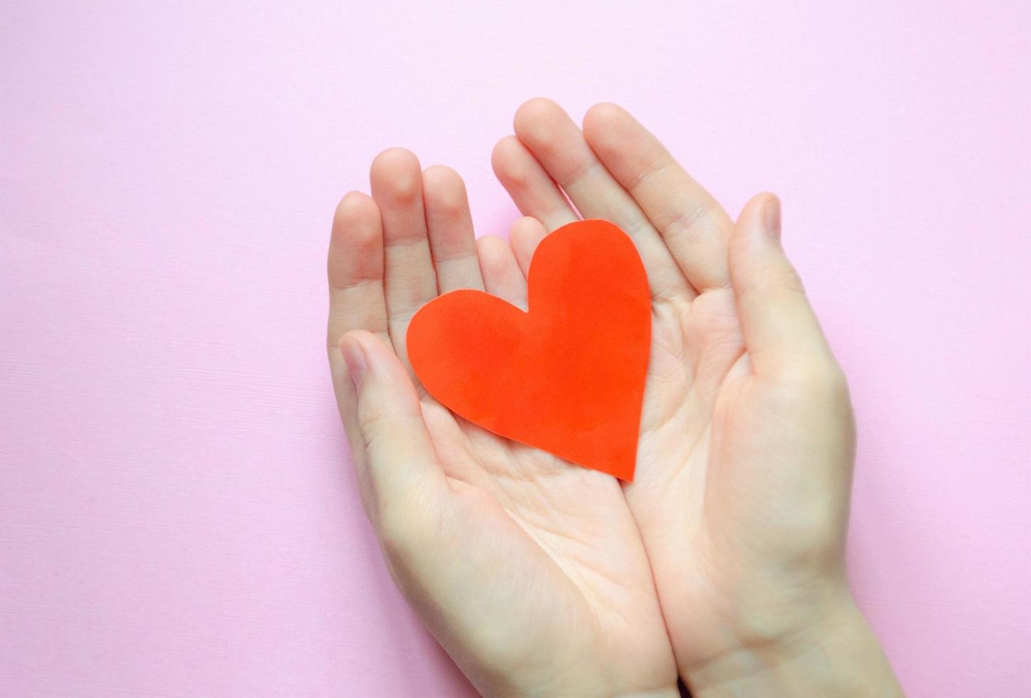 mano sostiene un corazón de papel rojo. vista superior. amor y st. concepto de día de san valentín. foto