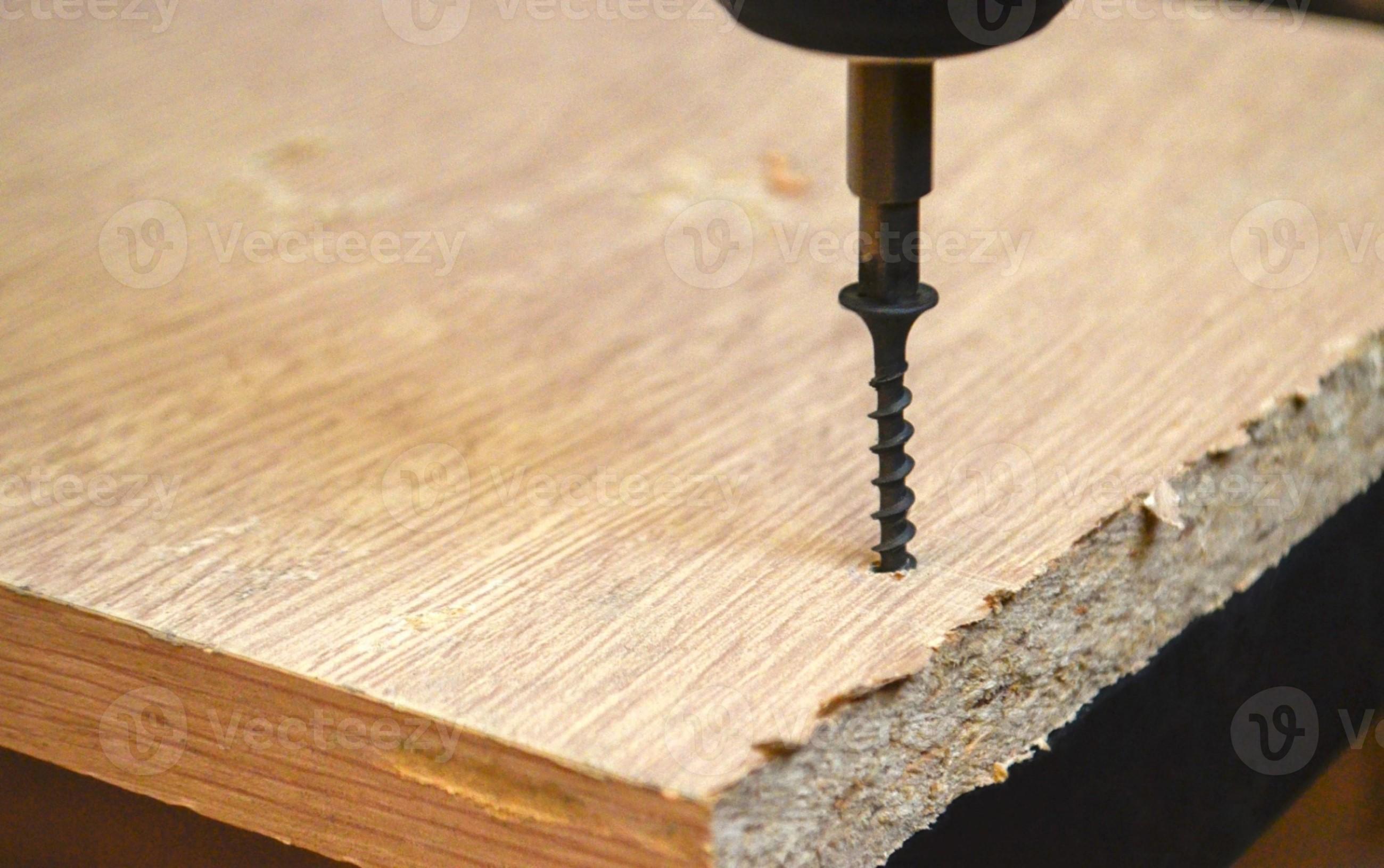 Drills a hole in a chipboard. Drill screwing a screw. 14609367 Stock