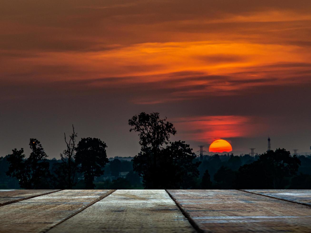 An old wooden table against the backdrop of the shadow of the forest with sunset at dusk. photo