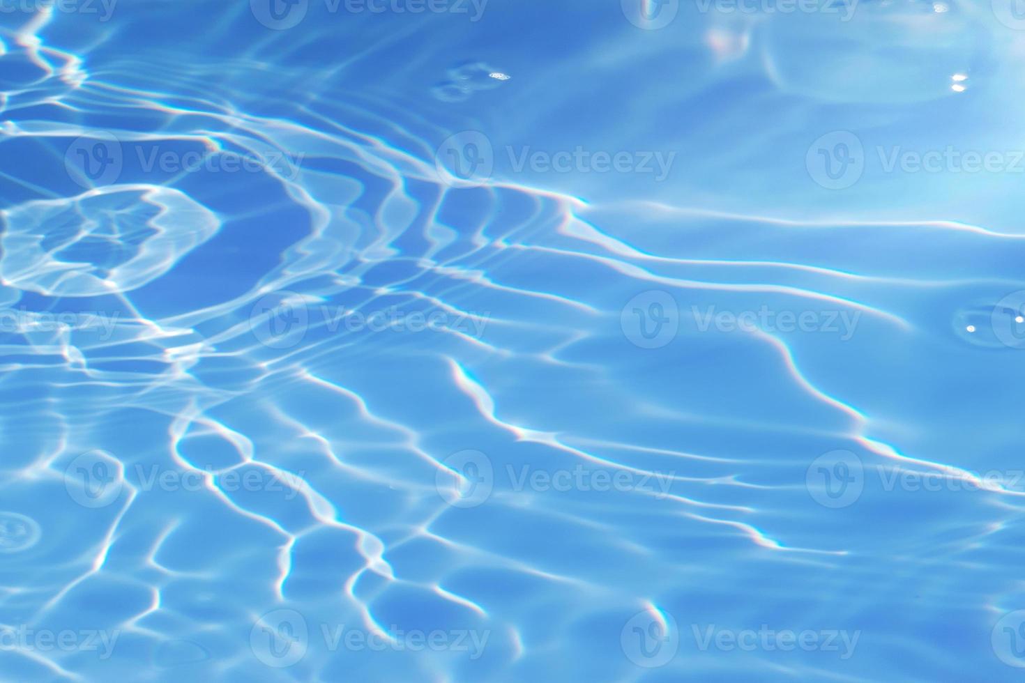 Defocus blurred transparent blue colored clear calm water surface texture with splashes and bubbles. Trendy abstract nature background. Water waves in sunlight with copy space. Blue watercolor shining photo